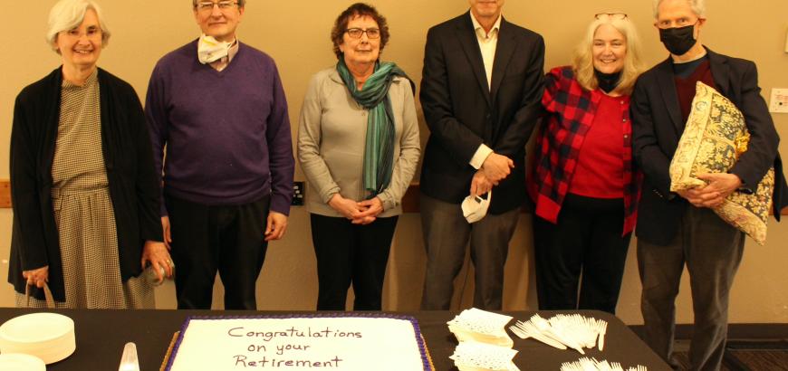 Path Ebrey, Bob Stacey, Mary O'Neil, John Findlay, Robin Stacey, and George Behlmer stand together being a cake that says Congratulations on Your Retirement